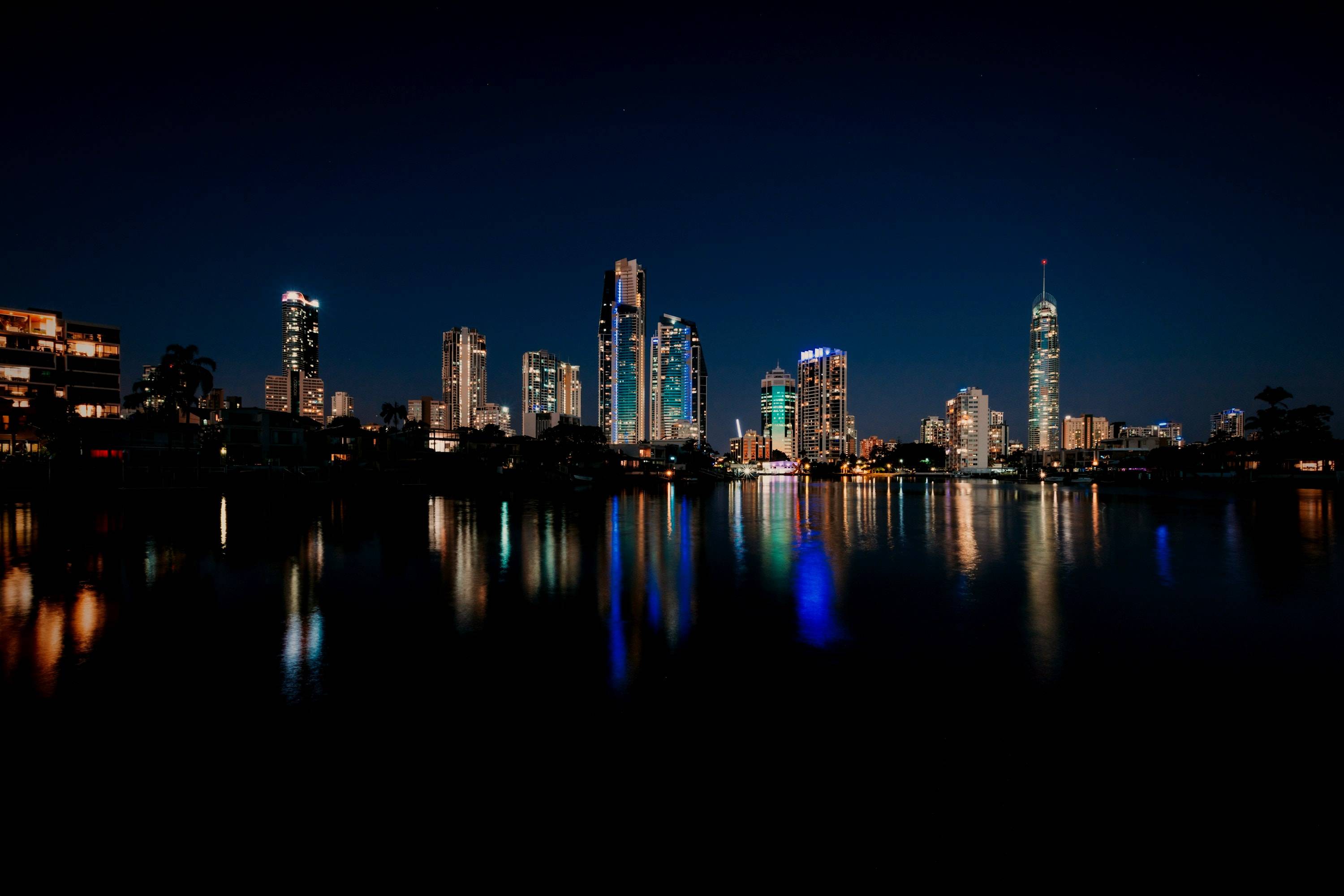 The Gold Coast skyline at night, its towers lit and mirrored in still water.